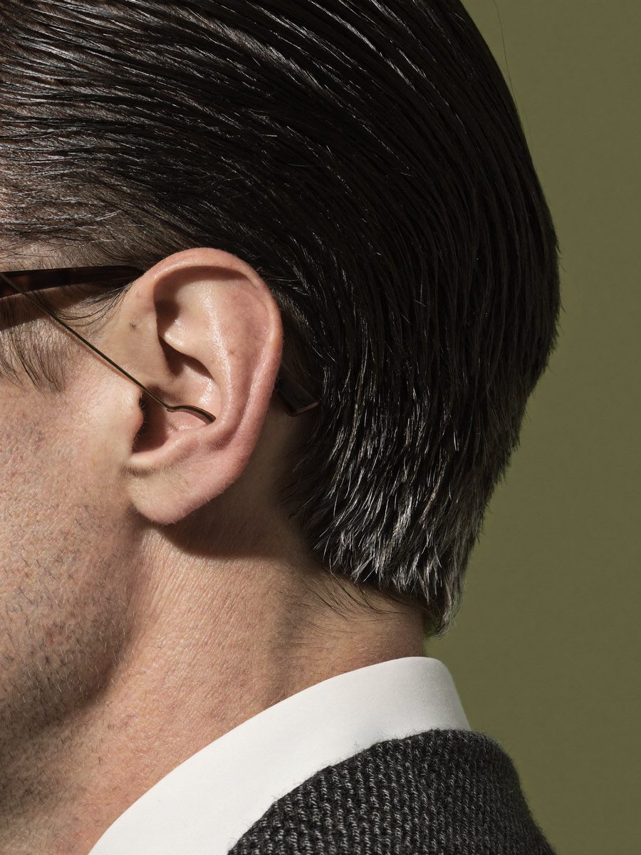Close-up of a dark, combed-back hairline with a streak of silver at the temple