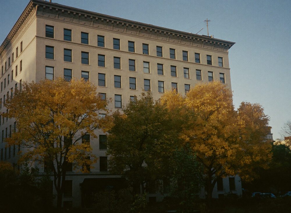 A pre-war apartment building behind autumn trees